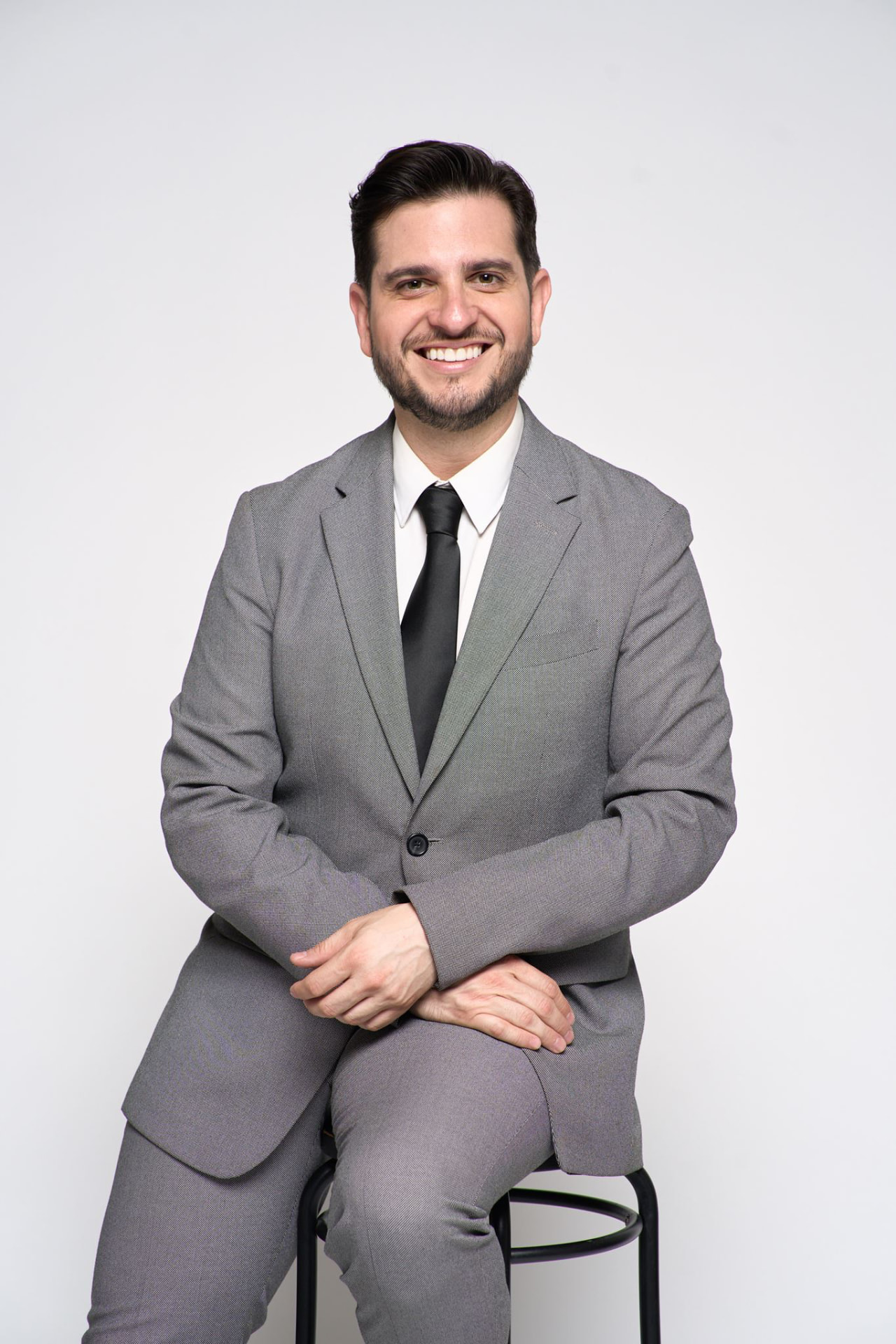 Nelson Carruyo Breglia, wedding planner, sentado con traje gris y corbata negra